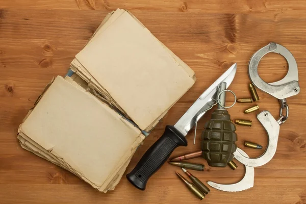 Pistola y libro de crimen y castigo. Lugar para tu mensaje. Cuchillo y libro sobre fondo de madera . — Foto de Stock