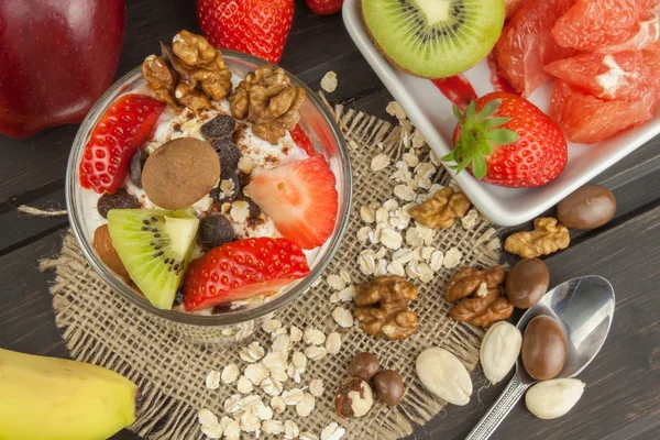 Preparing healthy breakfast for kids. Yogurt with oatmeal, fruit, nuts and chocolate. Oatmeal for breakfast. Preparing diet meals. A healthy diet for athletes. — Stock Photo, Image