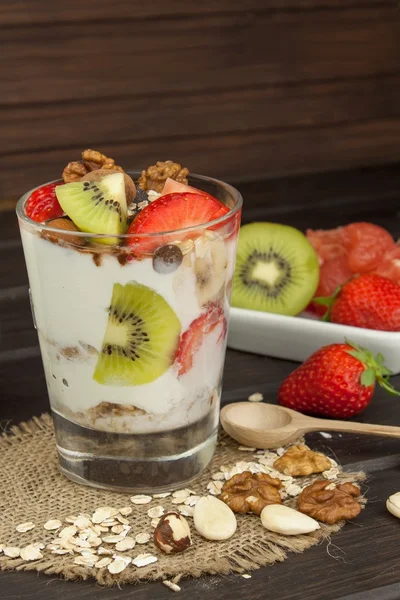 Preparing healthy breakfast for kids. Yogurt with oatmeal, fruit, nuts and chocolate. Oatmeal for breakfast. Preparing diet meals. A healthy diet for athletes. — Stock Photo, Image