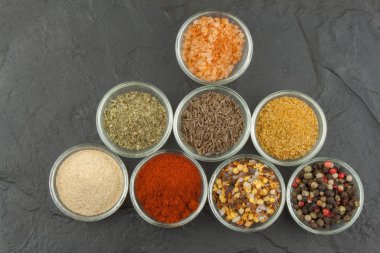 Çeşitli baharatlar cam kase kayrak bir arka plan üzerinde. Baharatlı yemek hazırlığı. Ana yemek için baharat. Baharat ticaret. Baharat mutfakta satışı.