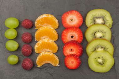 Ahududu, çilek, mandalina, üzüm ve kivi arduvaz arka plan üzerinde. Sağlıklı gıda mutfak masasının üzerinde. Menü hazırlama.