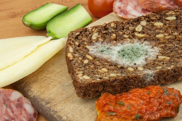 Moldy bread in wooden table. Unhealthy food. Spoiled food. — Stock Photo, Image