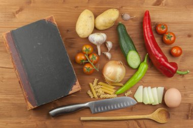 Ahşap bir masada eski yemek kitabı tarifleri. Cook sağlıklı sebze. Ev diyet gıda hazırlanması. Farklı sebze çeşitleri.