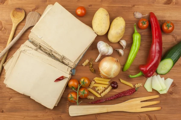 Oude kookboek recepten op een houten tafel. Kook gezonde groente. Voorbereiding van thuis dieet voedsel. Verschillende soorten groenten. — Stockfoto