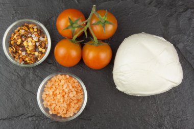 Taze mozzarella peyniri tahtada. Sağlıklı beslenme öğünleri. Misafirler için yemek hazırlıyorum. Geleneksel yemek. Mozzarella ve domates. Koyu gri arka plan.