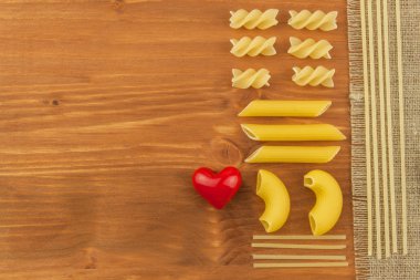 Makarna dekorasyonu. Ev yapımı yemekler hazırlıyorum. Ahşap arka planda farklı makarna çeşitleri. Menüyü oluşturma. Metniniz için yer.