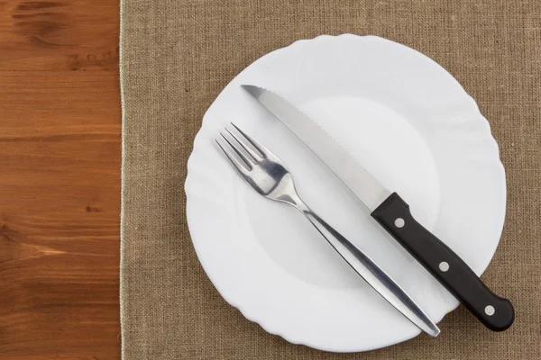 Empty white plate with knife and fork on a wooden table. Waiting for food. Home dining. Directly above view of table setting. Diet food. — Stock Photo, Image