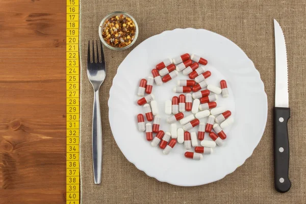 Ένα πιάτο με συμπληρώματα διατροφής και μαχαιροπίρουνα. Φαγητό διαίτης. Αυστηρή δίαιτα για τους αθλητές. — Φωτογραφία Αρχείου
