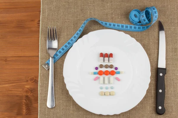 Diet products on a white plate. A plate of food supplements and cutlery. Diet food. Strict diet for athletes.