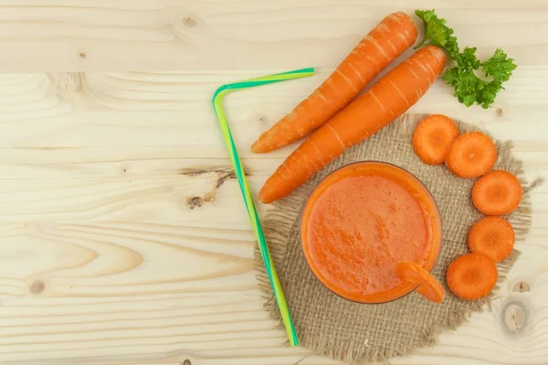 Segelas jus wortel dan wortel di atas meja kayu. Jus sehat yang penuh vitamin dan serat. Makanan diet. Segmen wortel pada latar belakang kayu . — Stok Foto