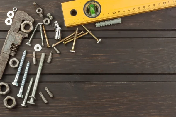 Störung im Werkzeug. Vorbereitung auf die häusliche Behandlung. verschiedene Werkzeuge, Schrauben und Muttern auf einem hölzernen Hintergrund. Werkzeugmechaniker. — Stockfoto