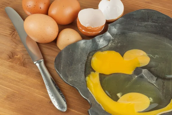Trasiga ägg på smidda metall skål. Inhemska ägg på ett träbord. Kvalitet proteinkälla. Metall skål av råa ägg och äggskal. — Stockfoto