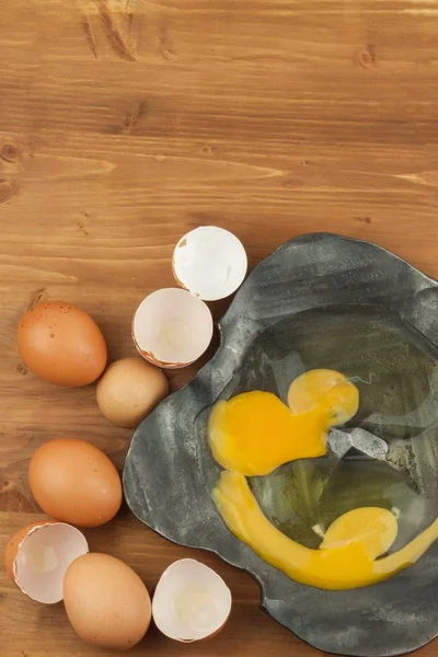 锻造金属碗上的破碎鸡蛋。木桌上的家用鸡蛋。优质蛋白质的来源。生蛋和蛋壳的金属碗. — 图库照片