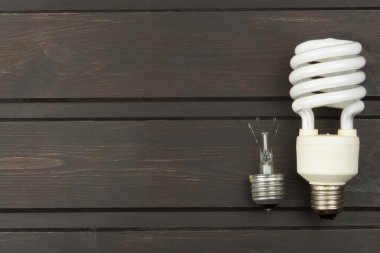Broken incandescent bulbs and new energy-saving light bulb on wooden background. Sales of light bulbs. Advertising on lighting technology.