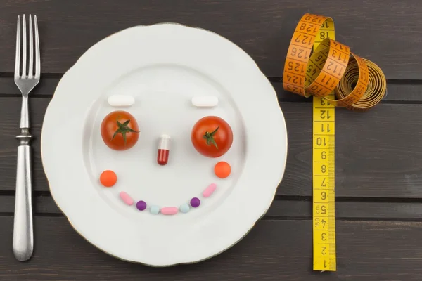 Ruokavalio ja lisäravinteet puinen pöytä. Tiukat laihdutusateriat. Laihdutusruokavalio. Tomaatit ja pillerit . — kuvapankkivalokuva