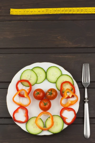 Comida de dieta em uma mesa de madeira. Refeições dietéticas rigorosas. Dieta de emagrecimento. Tomates, pepinos e pimentas em um prato branco . — Fotografia de Stock