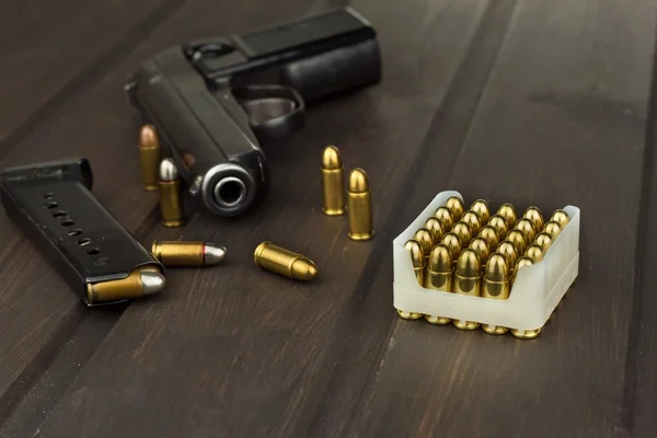 Pistol med ammunition på en mörka träbord. Försäljning av vapen och ammunition. Reklam på ammunition. Nya vapen och ammunition. Livsmedelsaffär ammunition. Leveranser av ammunition för försvar. — Stockfoto