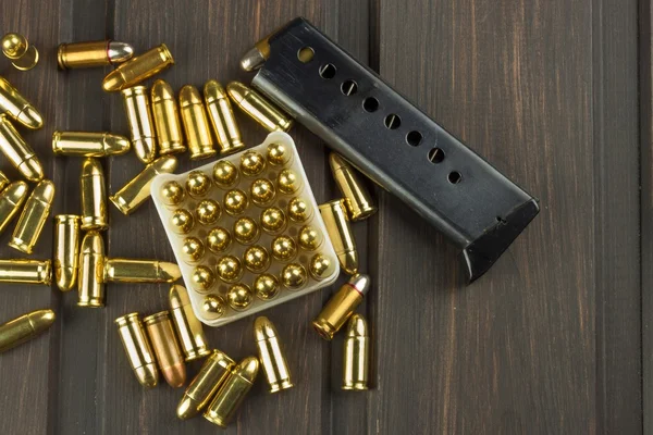 Handgun with ammunition on a dark wooden table. Sales of weapons and ammunition. Advertising on ammunition. New gun and ammunition. Grocery ammunition. The supply of ammunition for the defense. — Stock Photo, Image