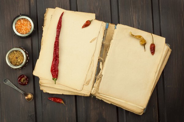 Recipe book and vegetables. Chili pepper and tomatoes. Food preparation according to the old recipe book. Grandma's recipe book. Old recipes for cooking.