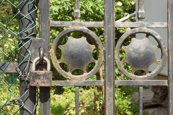 Old rusty lock on a metal gate into the garden. Lock on the iron gate. Symbol imprisonment and slavery. Property security chain. Closed iron gate with a lock. Safe lock.