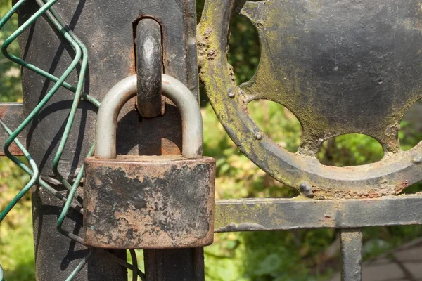 Παλιά σκουριασμένα κλείδωμα σε μια μεταλλική πύλη στον κήπο. Εξασφαλίστε στην πύλη σιδήρου. Σύμβολο φυλάκιση και τη δουλεία. Το κατάλυμα αλυσίδα ασφαλείας. Κλειστή πύλη σιδήρου με μια κλειδαριά. Κλειδαριά χρηματοκιβωτίου. — Φωτογραφία Αρχείου