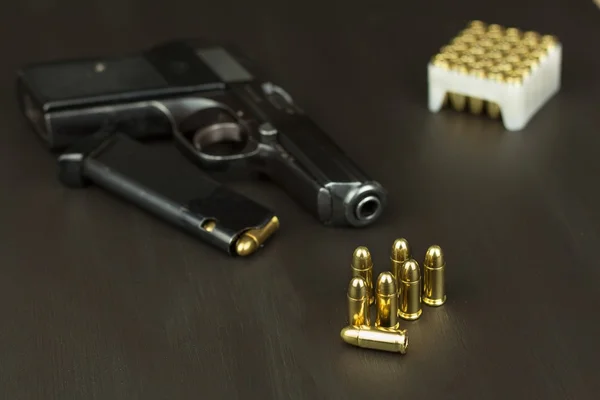 Handgun with ammunition on a dark wooden table. Sales of weapons and ammunition. Advertising on ammunition. New gun and ammunition. Grocery ammunition. The supply of ammunition for the defense. — Stock Photo, Image