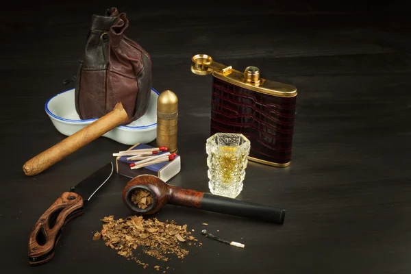 Old tobacco pipe and spilled tobacco, used on a black wooden background. Shabby old tobacco pipe. Wooden tobacco pipe on a black background. Relaxing with a tobacco pipe. Quiet place. Chain smoker. — Stock Photo, Image