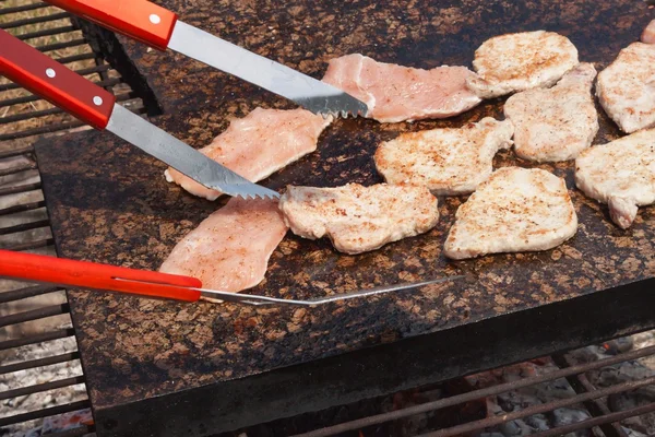 Barbacoa chuletas de cerdo y pollo en una encimera de granito caliente. Fiesta de verano con barbacoa. Asar en una piedra caliente . — Foto de Stock