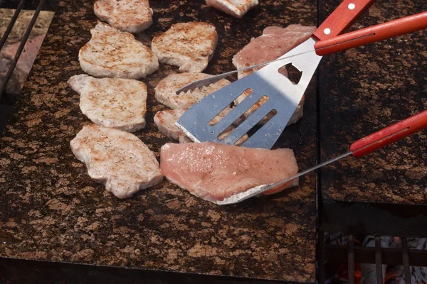 Costeletas de porco de churrasco e frango em uma bancada de granito quente. Festa de verão com churrasco. Grelhar em uma pedra quente . — Fotografia de Stock