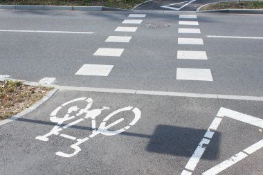 Asfaltta bisiklet yol tabelası. Bisiklet yol işareti ve bisiklet binici. Yolun karşısını geçiyor. Karikatürler trafik işaretleri.