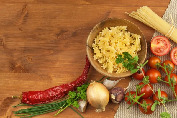 Těstoviny s rajčaty a petrželkou na dřevěném podkladu. Připravit dietní stravu. Recept na jednoduchou večeři. Tradiční těstoviny se zeleninou. — Stock fotografie