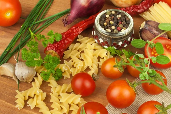 Rå pasta med tomater och persilja på trä bakgrund. Beredning diet mat. Receptet för en enkel middag. Traditionell pasta med grönsaker. — Stockfoto