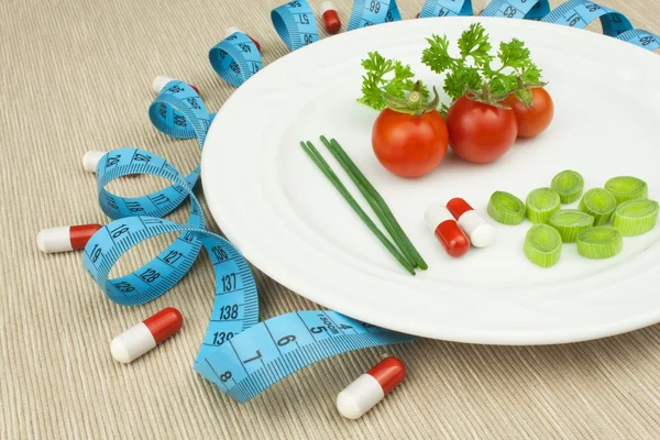 Dieta rigorosa contra a obesidade. Dieta vegetal dietética. Tomates em uma chapa. Legumes crus em uma chapa branca e uma fita métrica . — Fotografia de Stock