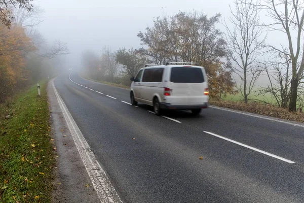 Cars in the fog. Bad autumn weather and dangerous automobile traffic on the road. Light vehicles in fog. Slippery road. Dangerous driving.