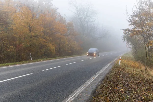 Cars in the fog. Bad autumn weather and dangerous automobile traffic on the road. Light vehicles in fog. Slippery road. Dangerous driving.