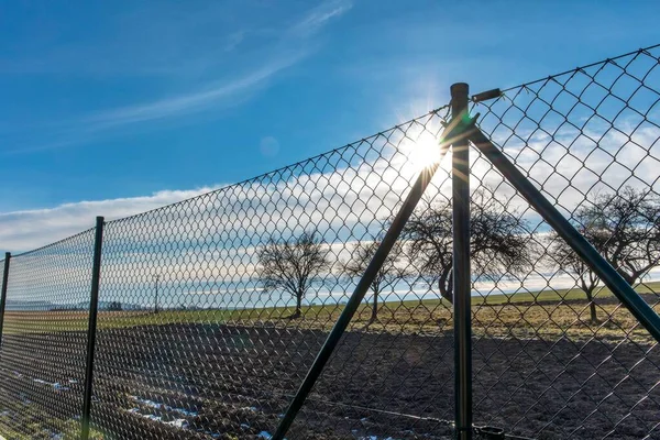 Green wire fence. Private property. Fence around the garden. Sunrise behind the fence.