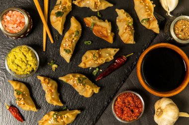 Soya soslu kızarmış hamur tatlısı ve kırmızı biber. Etle doldurulmuş Çin böreği. Siyah arka planda soya soslu ev yapımı etli börek..