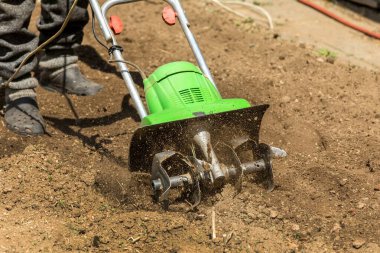 Bahçıvanlık. Çiftlikte bahar işi. Elektrikli ekiciyle arazi ekimi. İnsanlar elektrikli ekiciyle toprağı sürerler..