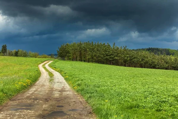 Road to the storm. Dark storm clouds and dirt road in Czech Republic. Spring stormy weather in the Czech countryside.