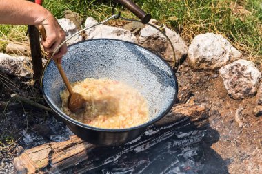 Şenlik ateşinde kaynayan metal kazan. Açık ateşte yemek pişirmek, kamp yapmak. Kamp ateşinde geleneksel gulaş hazırlığı.