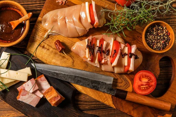 Raw chicken fillet on a cutting board with rosemary, spices, tomatoes and pepper. Portions of meat on the table. Keto diet.