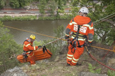 Kadan, Czech Republic, June 6, 2012: Exercise rescue units. Training rescue people in inaccessible terrain at the dam Kadan. Recovery using rope techniques clipart