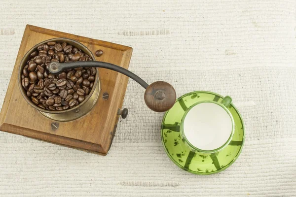 Spilled coffee beans, coffee mug, old coffee grinder — Stock Photo, Image