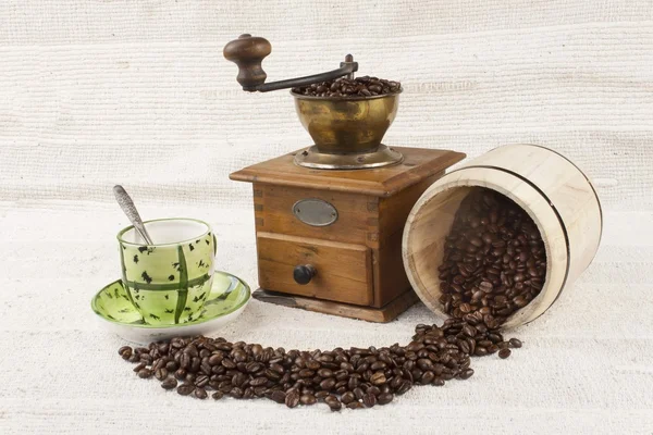 Пролитые кофейные зерна, кофейная кружка, старая кофемолка — стоковое фото