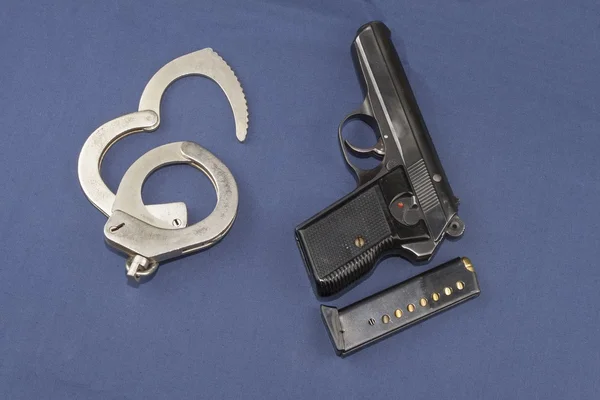 Gun, magazine and police handcuffs lying on the table — Stock Photo, Image