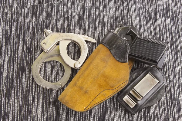 Firearm lying on the table, metal police handcuffs — Stock Photo, Image