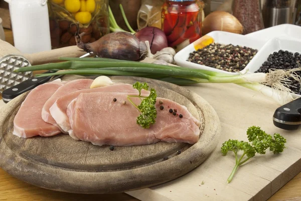 Accueil Préparation des aliments dans la cuisine, rôti de porc sur gril, porc cru sur planche à découper et légumes — Photo