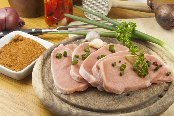 Accueil Préparation des aliments dans la cuisine, rôti de porc sur gril, porc cru sur planche à découper et légumes — Photo