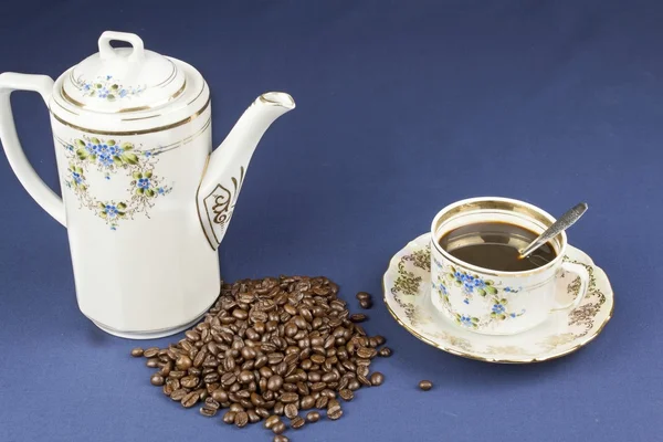 Tasse à café sur la table avec une nappe bleue, versé des grains de café — Photo