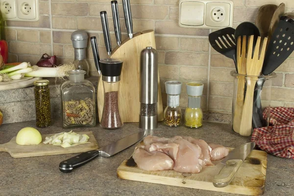 Hausaufgaben Hühnerfleisch, Hähnchenbrustfilet in Scheiben schneiden, Küchentisch mit Zutaten zum Kochen — Stockfoto